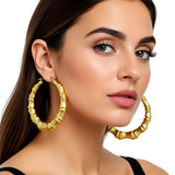 Woman wearing gold hoop earrings on a white background